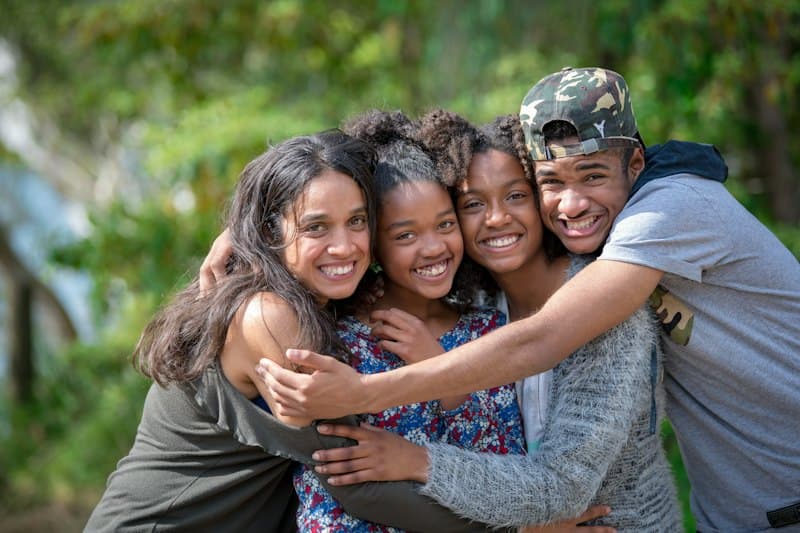 Família abraçada e sorrindo ao ar livre