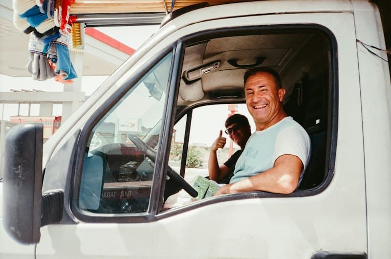 Motorista sorrindo na cabine de uma van de trabalho